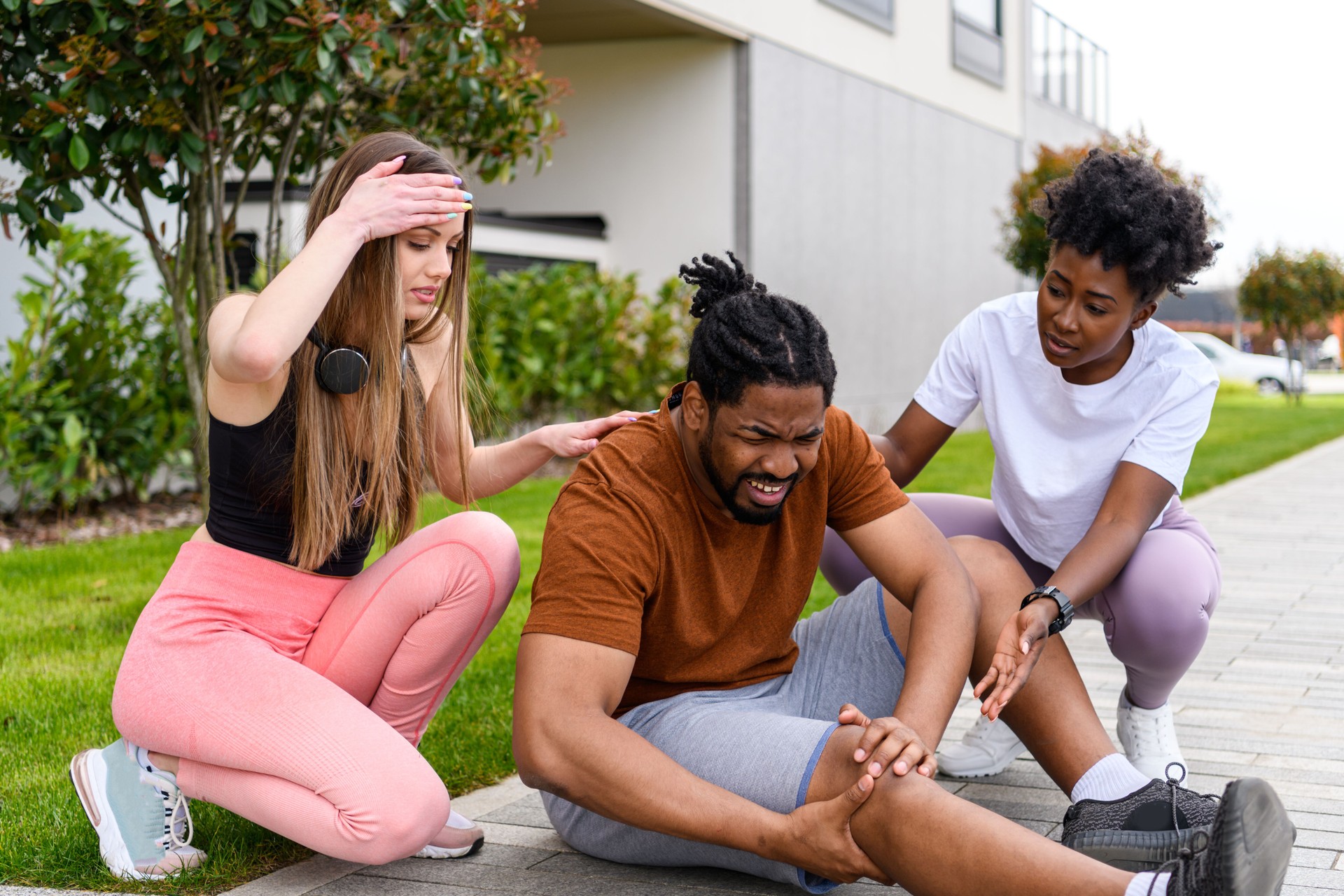 A Couple of Multicultural Female Friends is Helping a Man with a Leg Injury.